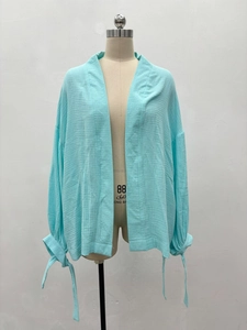 Détail du cardigan bleu clair en tissu texturé avec poignets à nouer élégants