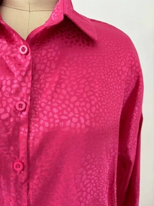 Détail d'une chemise rose rouge à imprimé animal avec col classique et boutons assortis