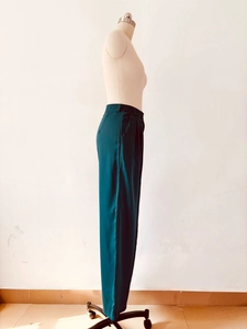 Detail view of dark green satin wide-leg trousers showing smooth fabric and side pocket