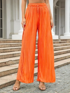 Detailed view of orange pleated wide-leg trousers with drawstring elastic waistband