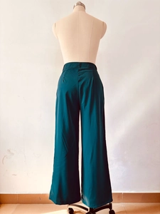 Rear view of high waisted dark green wide leg trousers on a mannequin with draping fabric
