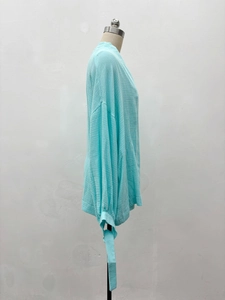 Détail du tissu en mousseline bleu clair et des poignets noués sur le haut ample
