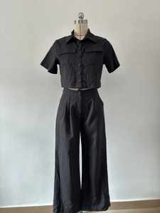 Detail of short sleeve crop top with chest pockets and wide leg pants in black cotton