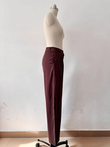 Detail view of burgundy high-waisted wide-leg trousers with side pocket and smooth texture