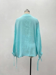 Détail de la chemise en coton bleu clair avec poignets à nouer et coupe décontractée