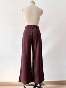 Rear view of high waisted wide leg trousers in deep chocolate brown with back pleat detail