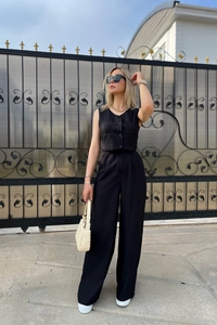 Detail of a chic black two-piece set with a cropped vest and high-waisted trousers