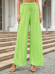 Detail of light green pleated wide-leg trousers featuring elastic waist and drawstring cord
