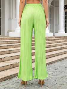 Back view of high waisted neon green pleated wide leg pants on a street staircase