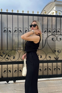 Detailed side view of a black two-piece set featuring a cropped vest and chic high-waist trousers