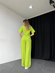 Detail of lime green two-piece set featuring short top and high-waist wide-leg pants