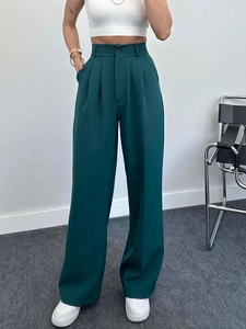 Close-up of high-waisted dark green wide-leg trousers with button detail and pleats