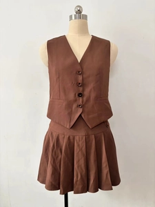 Detail of brown V-neck buttoned vest and high-waist pleated mini skirt two-piece set