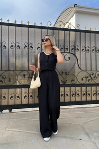 Detail view of black sleeveless button vest and high waist wide leg pants set on a model