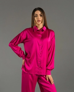 Detail of fuchsia satin two-piece set showing glossy fabric texture on shirt and trousers