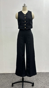 Detail of black V-neck vest with gold buttons and high-waist wide-leg trousers
