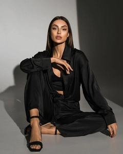 Detail of elegant black satin two-piece set featuring a long-sleeve shirt and draped pants