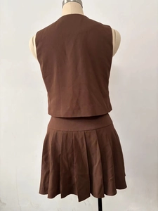Rear view of brown two-piece set featuring a sleeveless crop top and pleated mini skirt