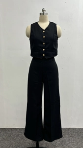 Detail of black two-piece suit featuring gold metal buttons on vest and wide-leg trousers