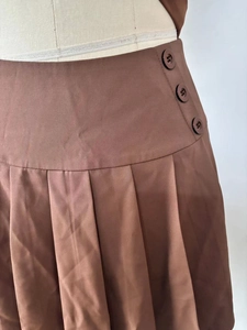 Detailed view of brown pleated skirt fabric with diagonal twill and side buttons decoration