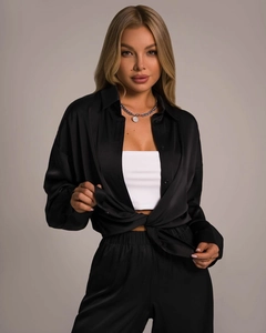 Detail of elegant black satin long sleeve shirt and matching trousers with smooth texture
