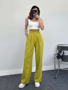 Detail of high waisted wide leg mustard trousers paired with a white ribbed crop top
