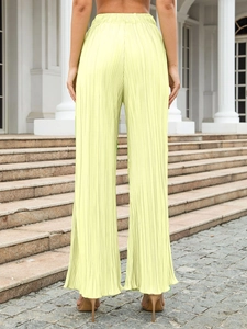 Detail of yellow pleated wide-leg trousers showing elastic waist and back view texture
