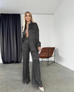 Détail de chemise en satin noir et pantalon à texture léopard sur un mannequin femme