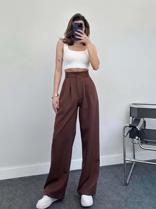 Detail of high-waisted dark brown wide-leg trousers featuring a sharp front crease line