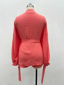 Détail d'un ensemble deux pièces orange corail avec texture plissée et ceinture nouée