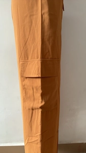 Gros plan du pantalon cargo caramel avec poche à rabat et détails de couture de qualité