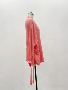 Détail d'une chemise en gaze rose avec coupe oversize et poignets à cordon