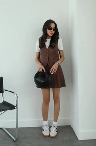 Detailed view of women's dark brown vest and pleated mini skirt set with white t-shirt