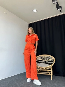Detailed view of women's bright orange short sleeve shirt and wide-leg trouser set