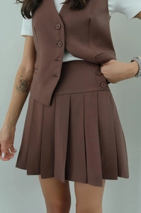 Detail of dark brown V-neck vest and matching pleated skirt with button waist detail