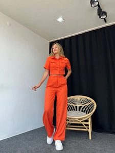 Detail of vibrant orange short sleeve crop shirt and high-waisted wide-leg linen pants set