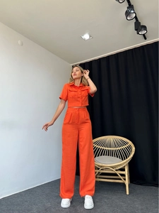 Detail of bright orange two-piece set featuring short sleeve shirt and wide-leg trousers