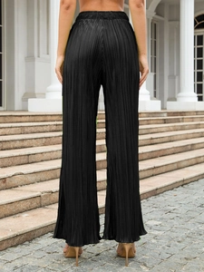 Detail of high-waist black accordion pleated wide-leg trousers with elastic waistband