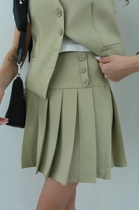 Detail of sage green sleeveless vest and pleated mini skirt set with buttons