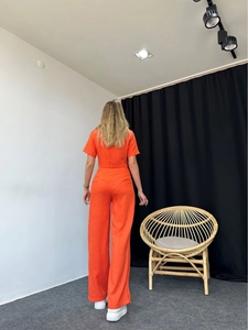 Rear view of vibrant orange two-piece women's set featuring short top and wide-leg trousers