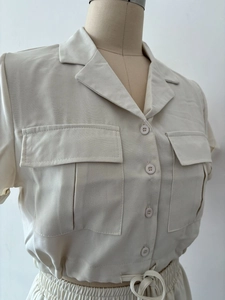 Détail de chemise cargo crème à manches courtes avec poches poitrine et taille à cordon