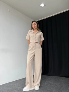 Detail of beige two-piece linen set featuring a buttoned short-sleeve top and wide-leg pants