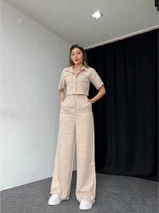 Detail of beige two-piece linen set featuring short sleeve button shirt and wide leg trousers