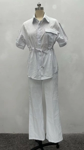 Detail of white two-piece set featuring short sleeve drawstring shirt and wide-leg trousers