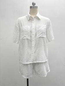 Detailed view of white eyelet lace embroidery on summer shirt collar and chest pockets