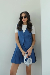 Detail view of blue sleeveless vest and pleated mini skirt set with premium suit fabric