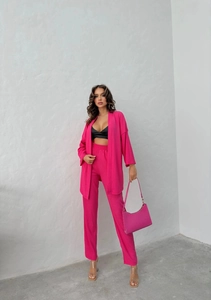 Detail of rose pink textured two-piece set with long jacket and high-waist trousers