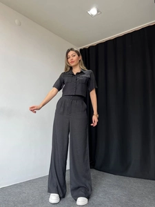 Detail of black short-sleeve button collar shirt and high-waisted wide-leg trousers outfit