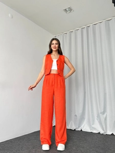 Detail eines orangefarbenen Leinen-Sets mit verkürzter Weste und hoch taillierter Hose