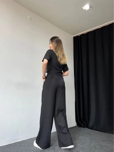 Rear view of minimalist black two-piece set featuring short-sleeve top and wide-leg pants